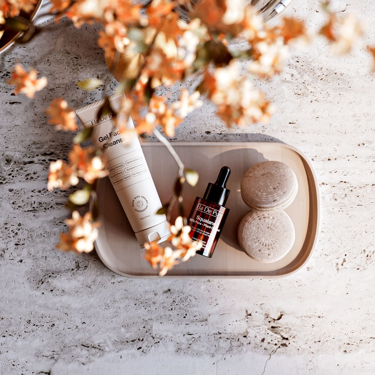 A stylish flat lay of luxury skincare products with a warm, botanical aesthetic.